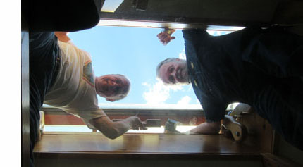 we are looking up at 3 guys standing on a glass platform about 4 feet below the ceiling and looking down at us and smiling.  There is a opening in the ceiling (about 3-4 feet on each side) and they are standing with their heads through the opening and outside.  We can see the sky above them.